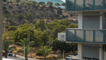 A multi-story building with balconies overlooking a hilly landscape with sparse vegetation.