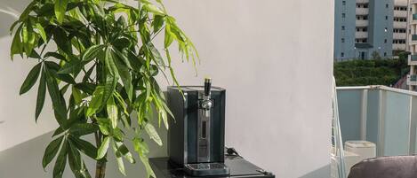 A potted plant, a water dispenser, and a seating area in a room with a view of buildings.