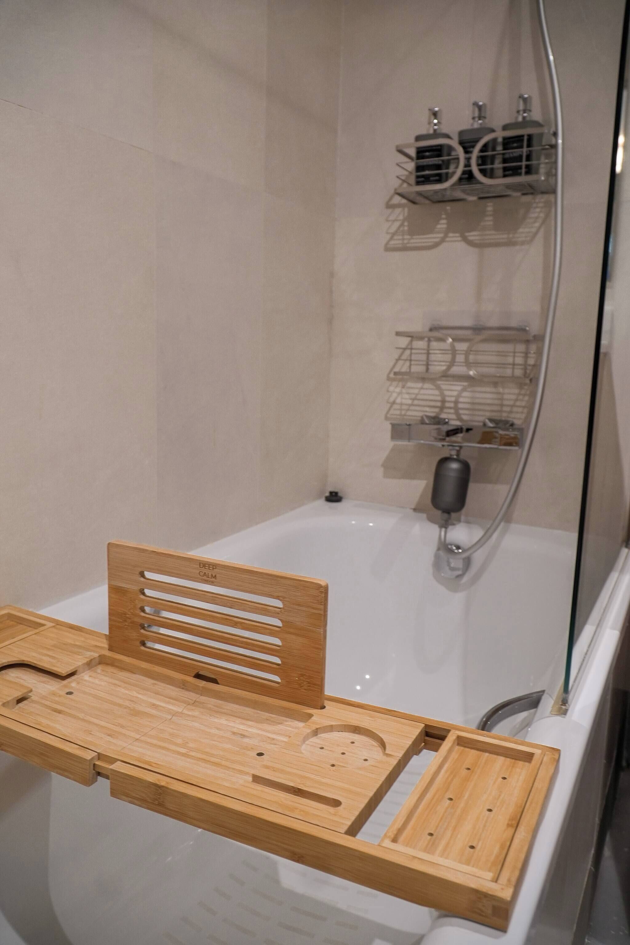 Un baño con una silla de madera, una bañera y una zona de ducha con estantes.