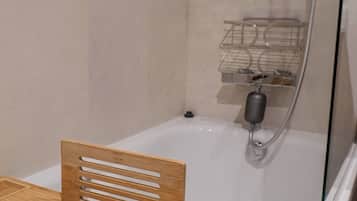 Un baño con una silla de madera, una bañera y una zona de ducha con estantes.