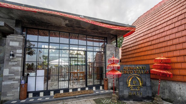 En bygningseingang med en stenfassade, store vinduer og et skilt med teksten 'ABIMANYU BUD VILLAS BALI'.