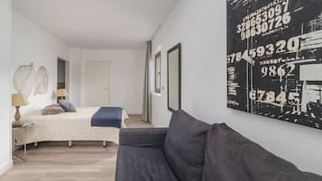 A bedroom with a bed, bedside tables, a grey sofa, and a wall with a large number-themed artwork.