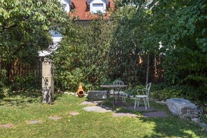 A garden with a stone bench, a table, and chairs. - Apartment "Haus im Ländle" with Lovely Terrace, Garden, and Wi-Fi (Volkertshausen)