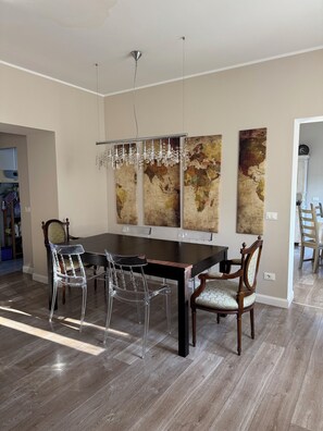 A dining area with a large table, chairs, and decorative wall art. - Panoramic villa in the Euganean Hills, between Bosco, Terme, and Venice (E. Fermi)