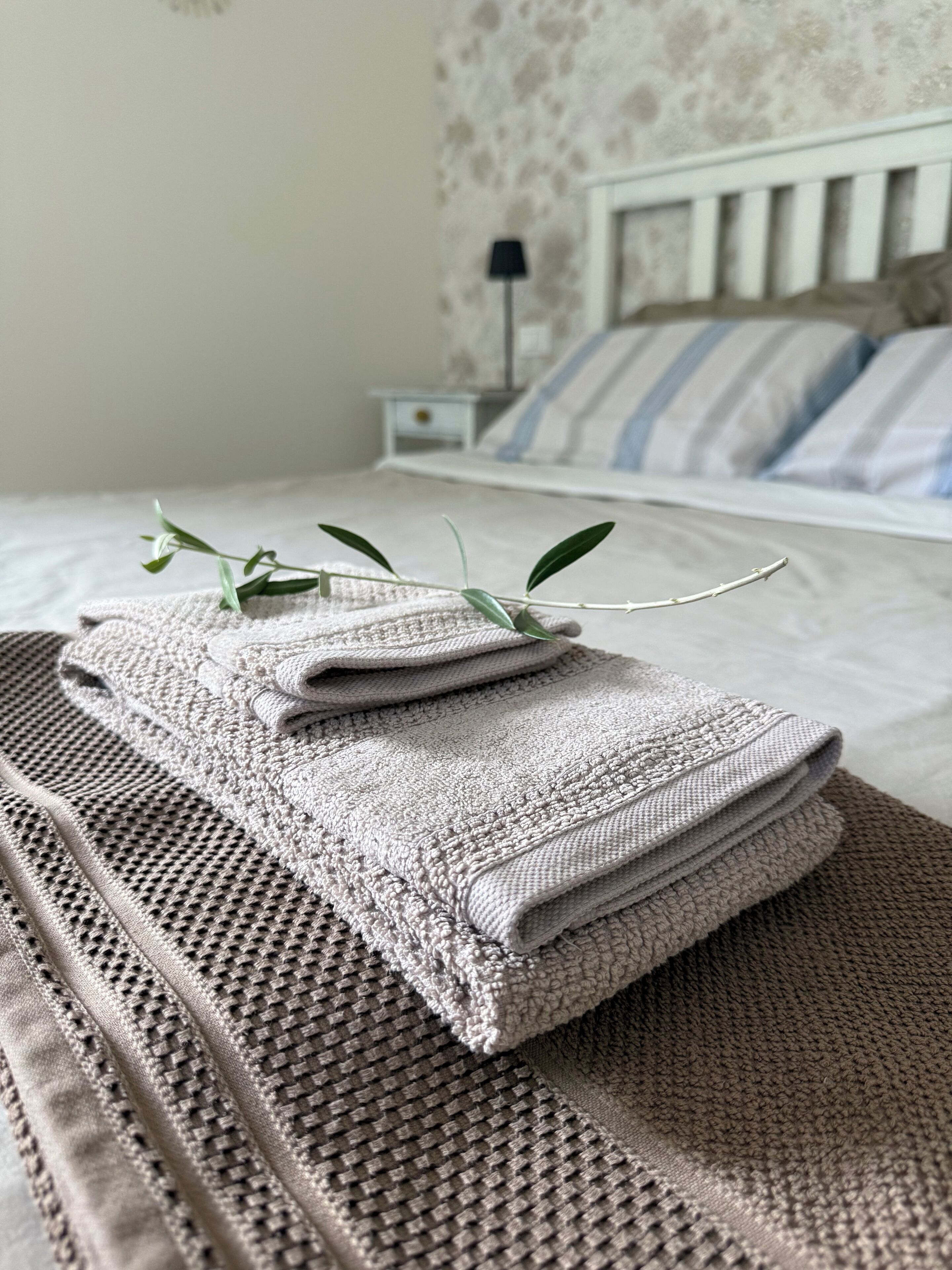 A neatly made bed with a striped pillow and a white headboard.