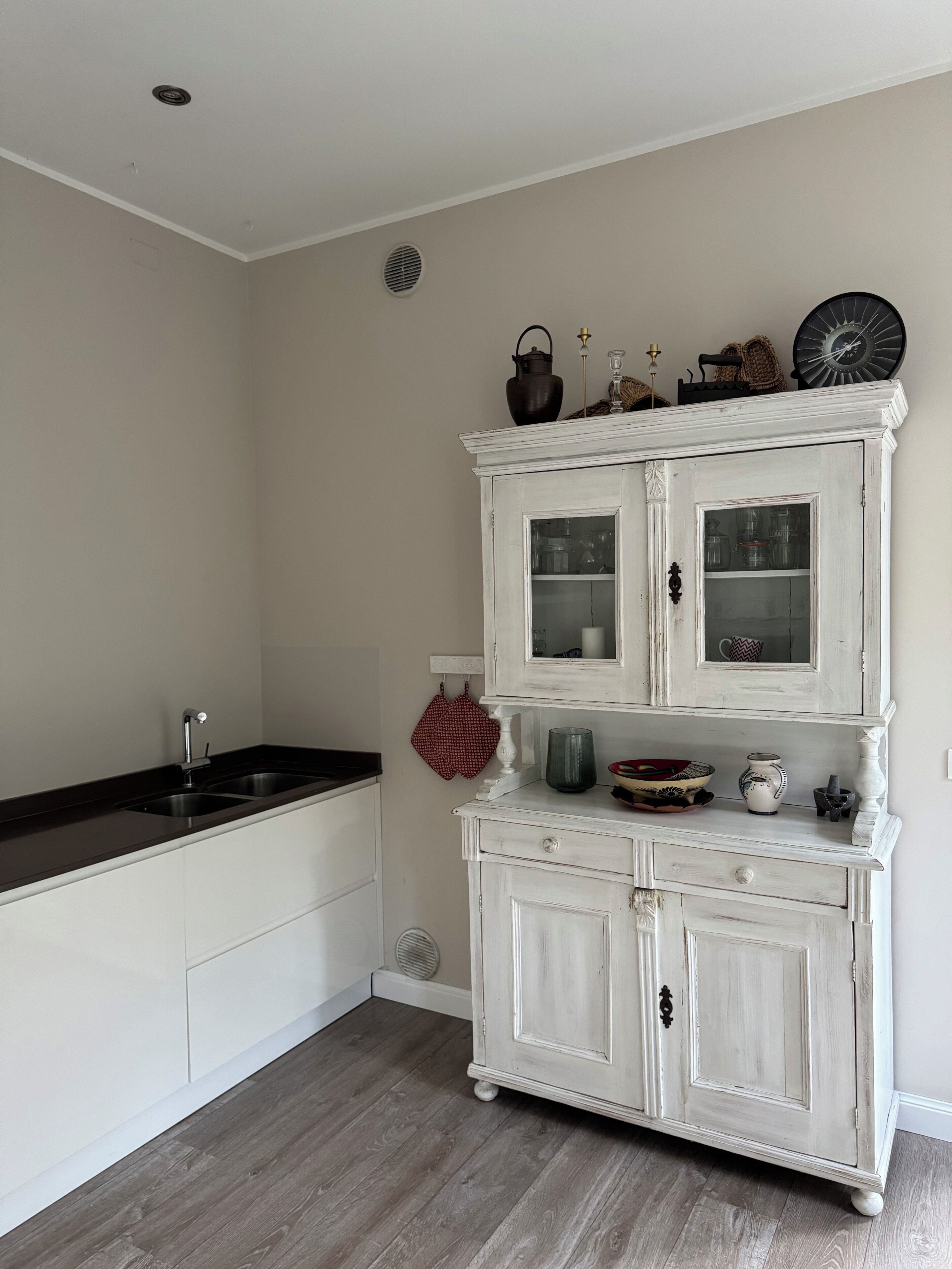 A kitchen with a white cabinet, a black countertop, and a red towel hanging on the wall.
