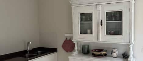 A kitchen with a white cabinet, a black countertop, and a red towel hanging on the wall.