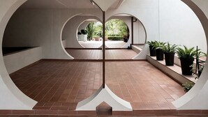 Un ambiente interno con pavimento piastrellato, pareti bianche e una serie di archi.