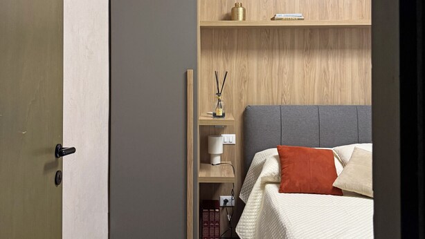 Una camera da letto con un letto, un comodino, una mensola in legno e una porta.