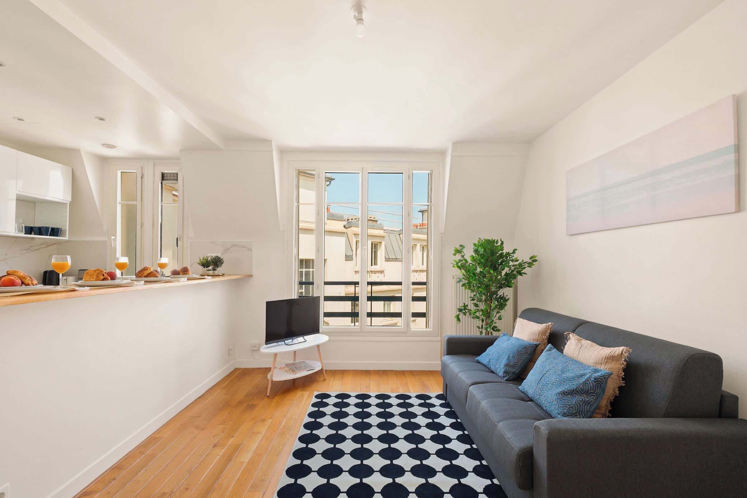 Ein modernes Wohnzimmer mit einem grauen Sofa, einem Couchtisch und einem schwarz-weißen Teppich.