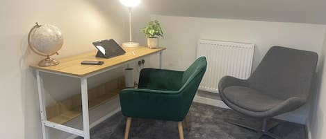 A study area with a desk, two chairs, a globe, a lamp, and a radiator.