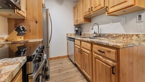 Une cuisine avec des meubles en bois, un réfrigérateur en acier inoxydable, une cuisinière et un four à micro-ondes.