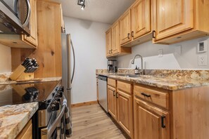 A kitchen with wooden cabinets, a stainless steel refrigerator, a stove, and a microwave. - Ski In/Out | A/C in Summer | Fresh Renovation 2026 (Steamboat Springs)