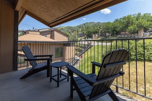A balcony with two Adirondack chairs and a small table, overlooking a residential area with houses and a clear sky. - Ski In/Out | A/C in Summer | Fresh Renovation 2026 (Steamboat Springs)