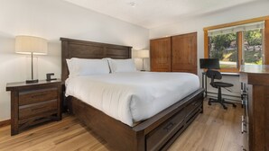 Une chambre à coucher avec un lit en bois, des tables de chevet, un bureau et une fenêtre.