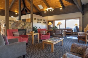 A cozy living room with a stone fireplace, red and gray sofas, and a large window offering a view. - Ski In/Out | A/C in Summer | Fresh Renovation 2026 (Steamboat Springs)