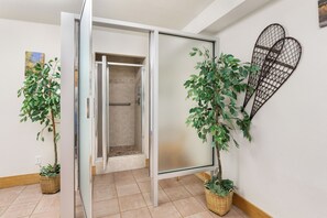 A room with a sliding glass door leading to a shower area, two potted plants, and a wall-mounted decorative item. - Ski In/Out | A/C in Summer | Fresh Renovation 2026 (Steamboat Springs)