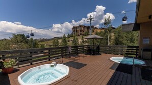 Une terrasse en bois avec deux bains à remous, une table avec des chaises et un panneau indiquant les règles du spa.