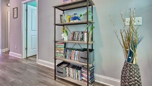 A hallway with a bookshelf filled with books and DVDs, a decorative vase with branches, and a door leading to another room. - 3-bedroom 2-bathroom house centrally located Camden side of Lake Wateree! (Camden)