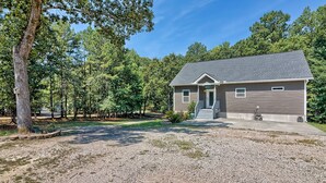 A single-story house with a covered porch, a gravel driveway, and a wooded area in the background. - 3-bedroom 2-bathroom house centrally located Camden side of Lake Wateree! (Camden)