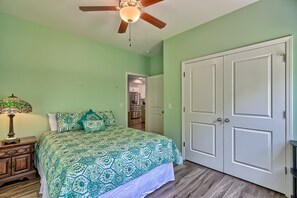 Ein Schlafzimmer mit Bett, Nachttisch, Lampe, Deckenventilator und Kleiderschrank.
