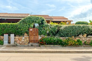 A residential property with a stone wall, a wooden gate, and a tiled roof. - Villetta Alberto: Apartment with Private Terrace, Garden, and Air Conditioning (Palau)