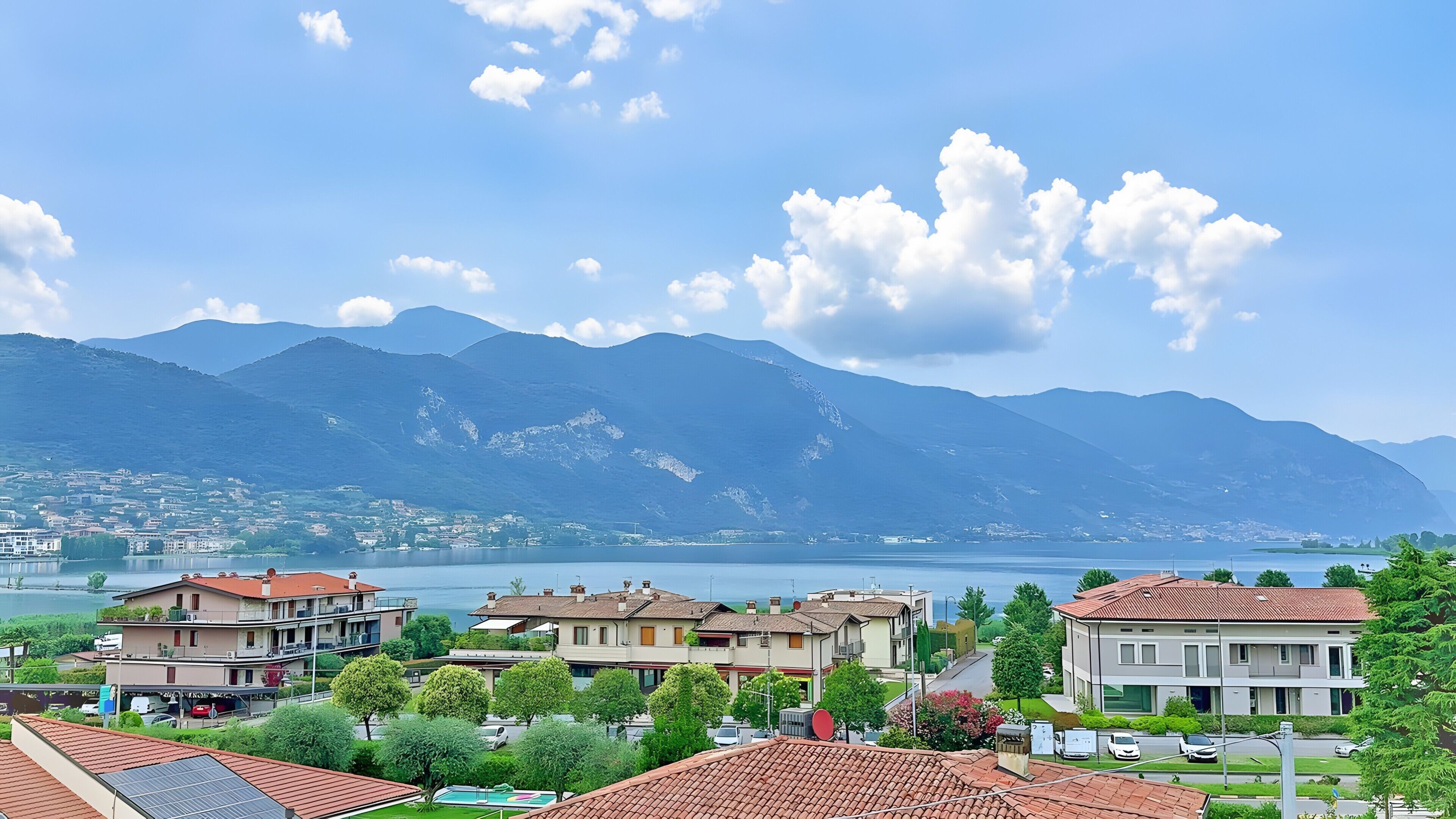 A residential area with houses, a lake, and mountains in the background.