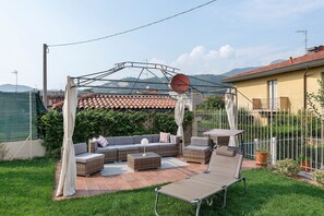 Eine Terrasse mit Gartenmöbeln, einer Pergola und Blick auf die umliegende Landschaft.