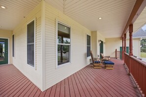 A covered porch with a wooden deck, two rocking chairs, and a green door. - This Charming farmhous style home is situated just outside Corvallis Montana. The space is well appointed and with plenty of space to spread out, making it a great base for exploring the Bitterroot Valley with family and friends. (Corvallis)