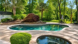 A swimming pool with a stone deck, surrounded by lush greenery and trees. - Chef's Château Suite B | Queen Bed, Pool + Hot Tub (Spalding County)