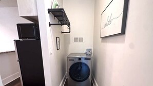 A laundry room with a washing machine, a refrigerator, and a microwave.
