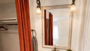 Un baño con un lavamanos de estilo vintage, un espejo con marco decorativo y un perchero para toallas.