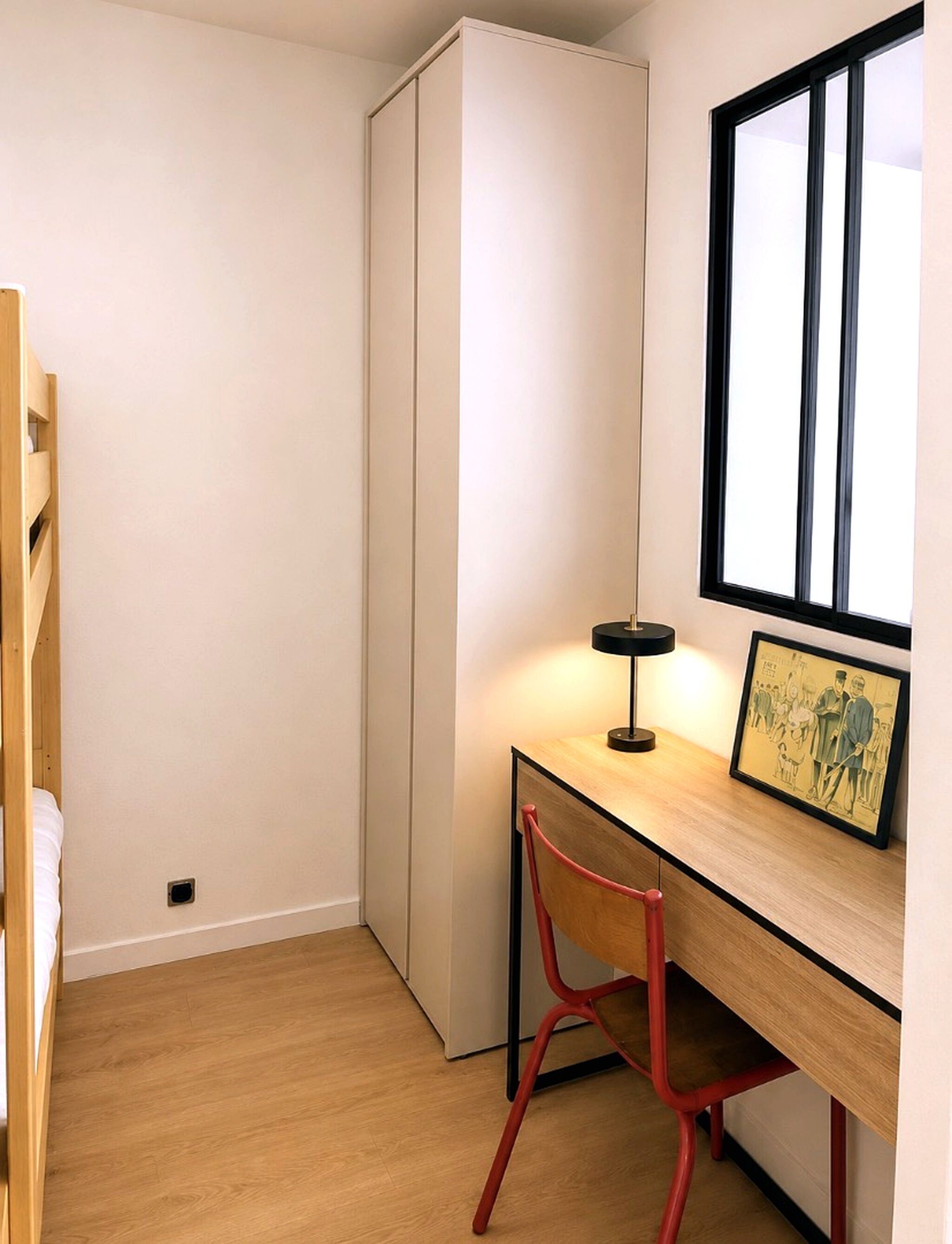 Un dormitorio con literas, un escritorio con silla, una lámpara y una ventana.