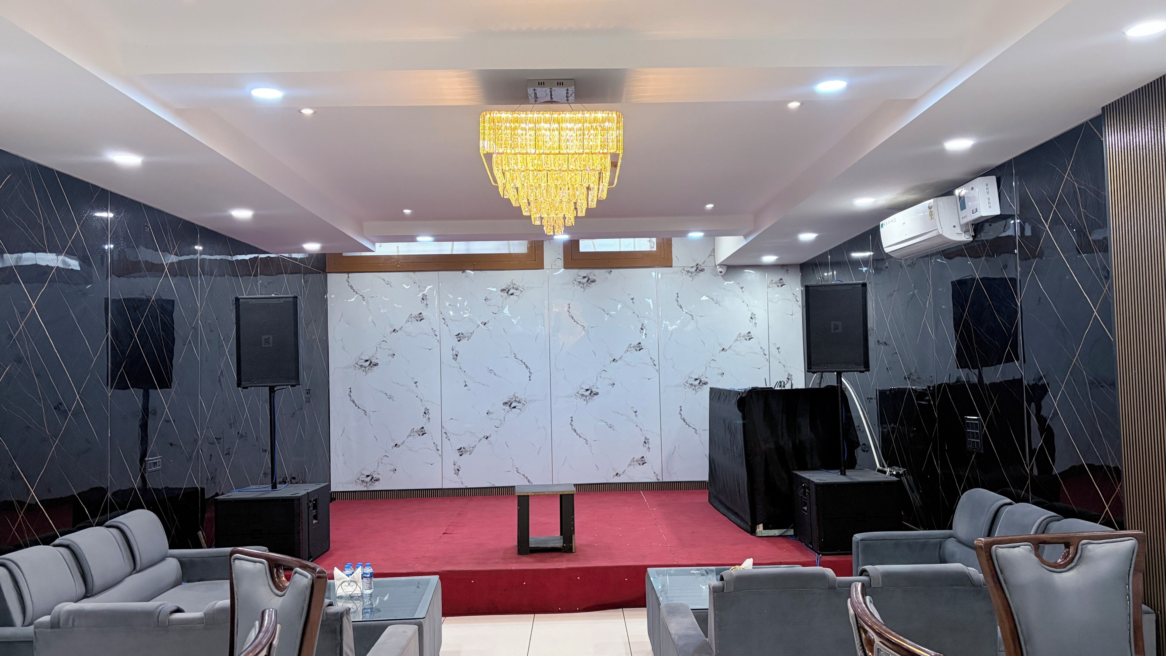 A conference room with a stage, seating, a chandelier, and marble walls.