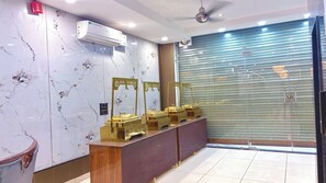 Zona de recepción de un hotel con paredes de mármol, un mostrador y una puerta con persiana cerrada.