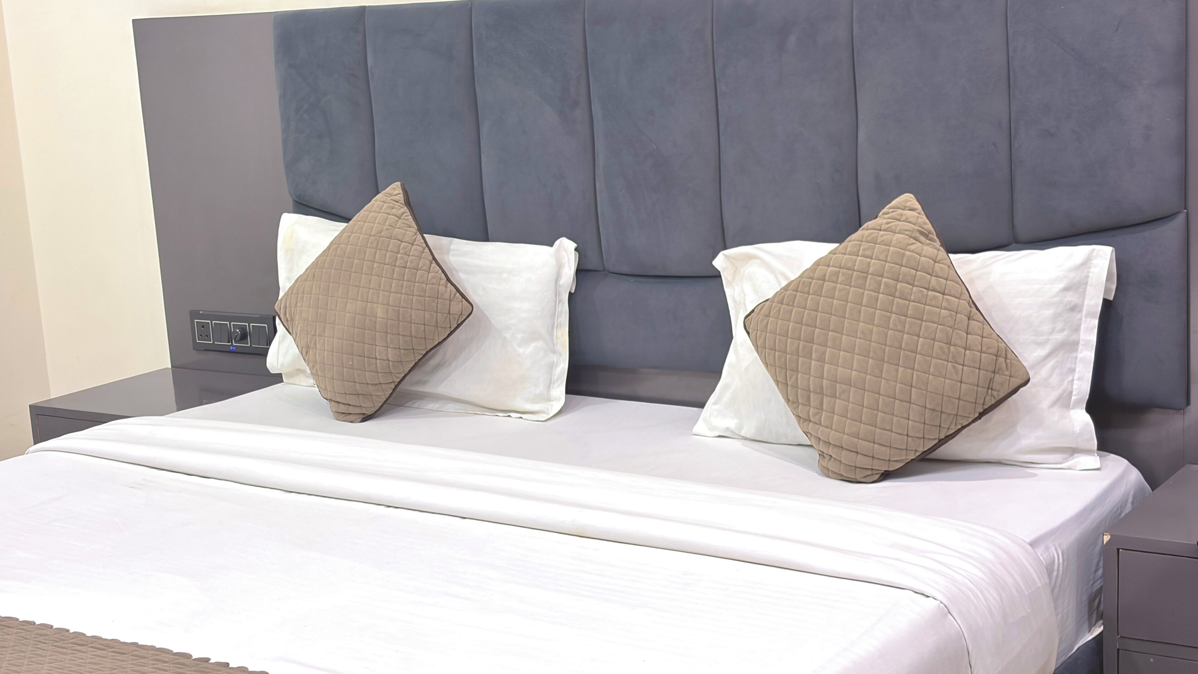 A bed with a headboard, two pillows, and a bedside table.