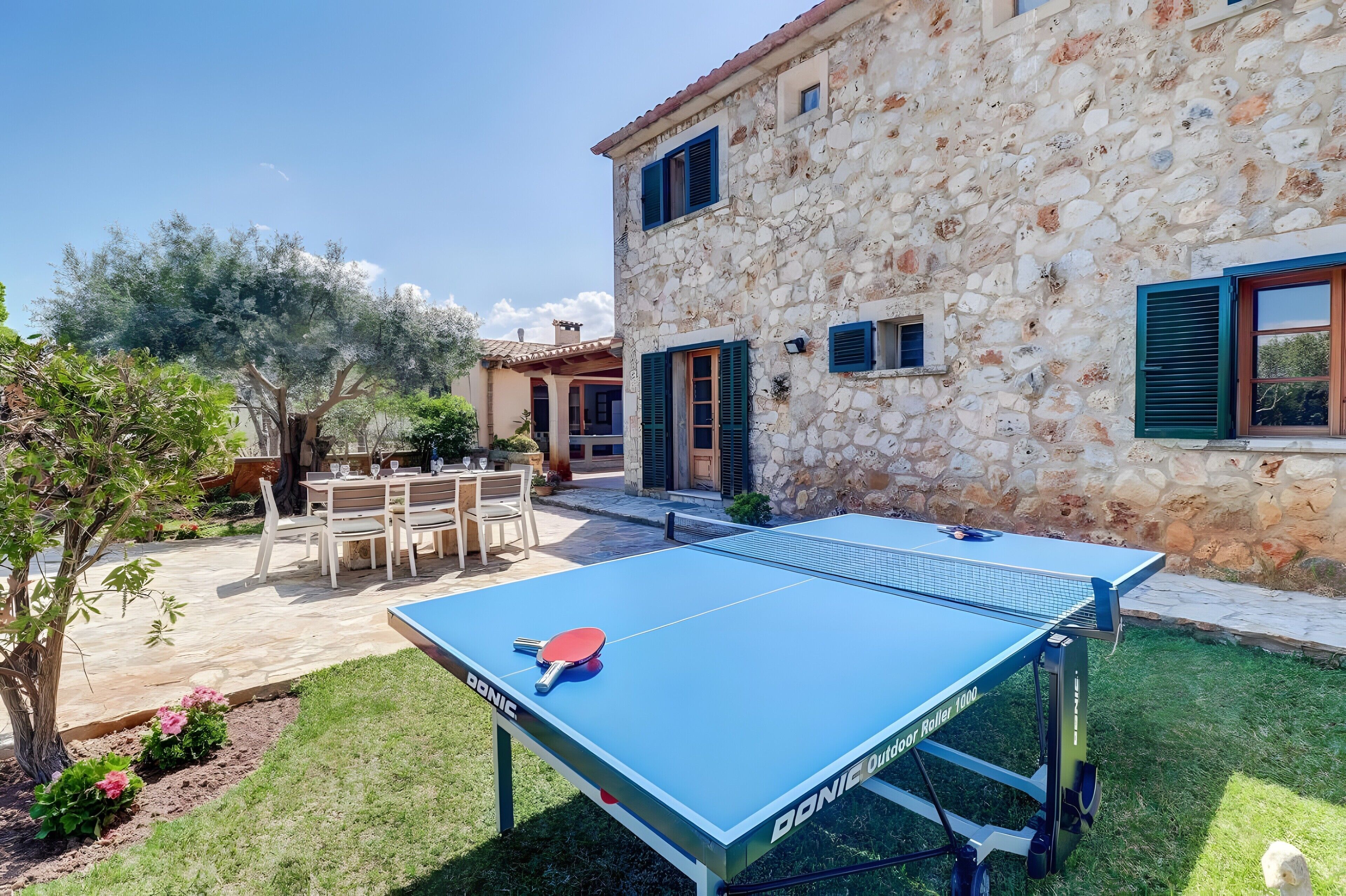 A stone building with a tennis table in the yard.