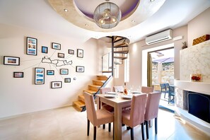 A modern dining area with a spiral staircase, a dining table set for four, and a wall with framed photographs.