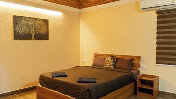 A bedroom with a wooden bed, a nightstand, a wall-mounted air conditioner, and a painting of a tree.