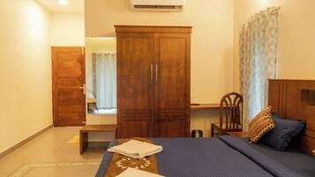 A bedroom with a bed, a wardrobe, a desk, and an air conditioning unit.