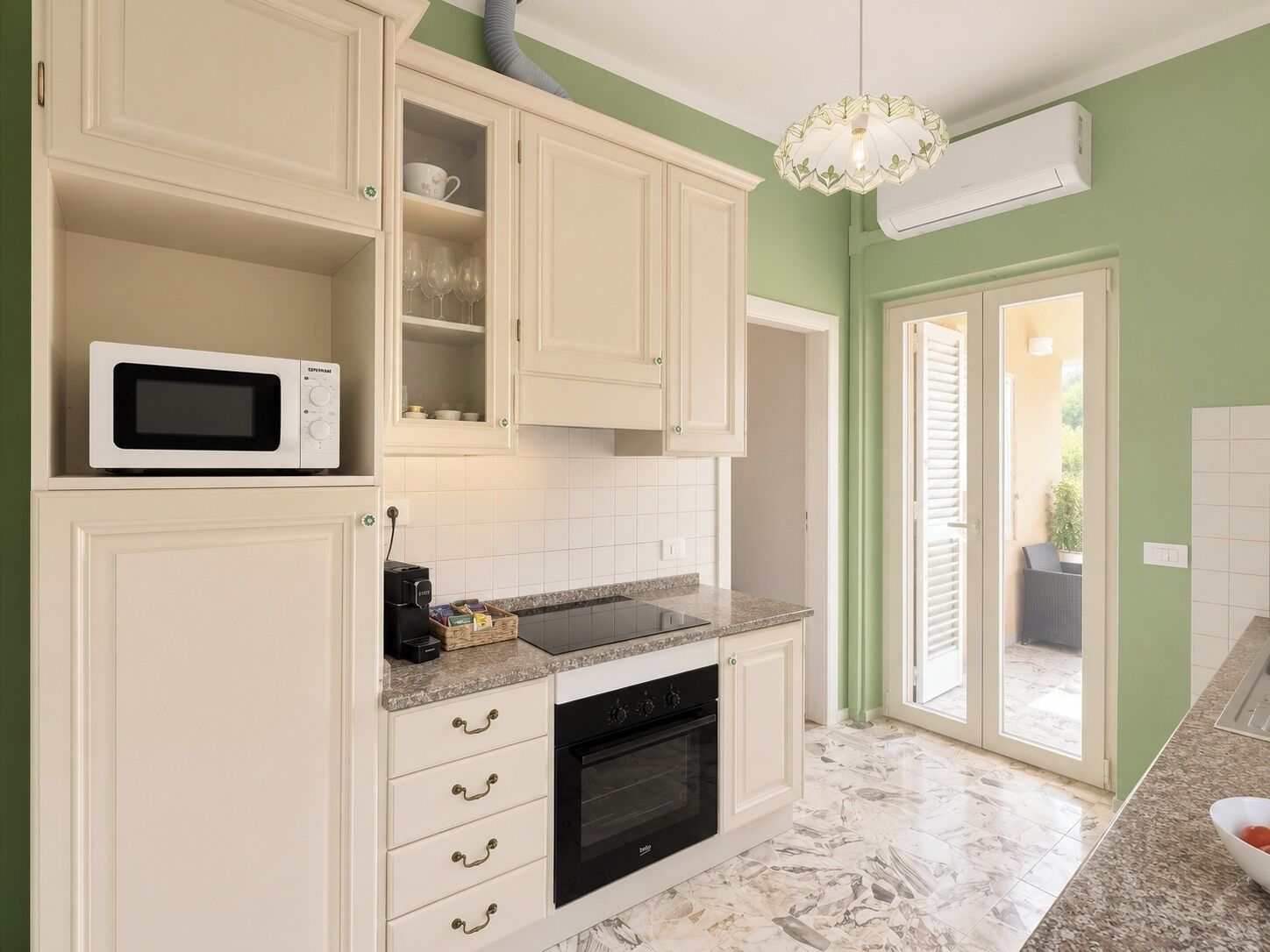 A kitchen with white cabinets, a microwave, a stove, and a countertop with a basket of items.