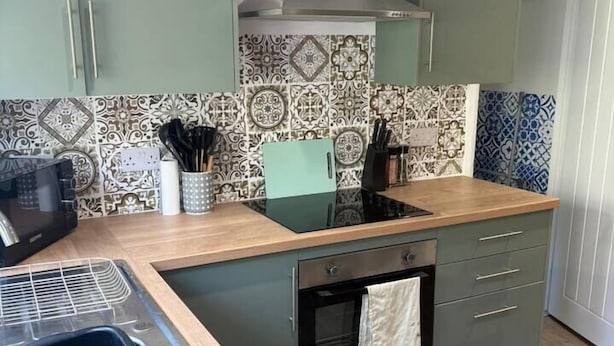 Una cocina con horno empotrado, extractor de acero inoxidable y salpicadero decorado.