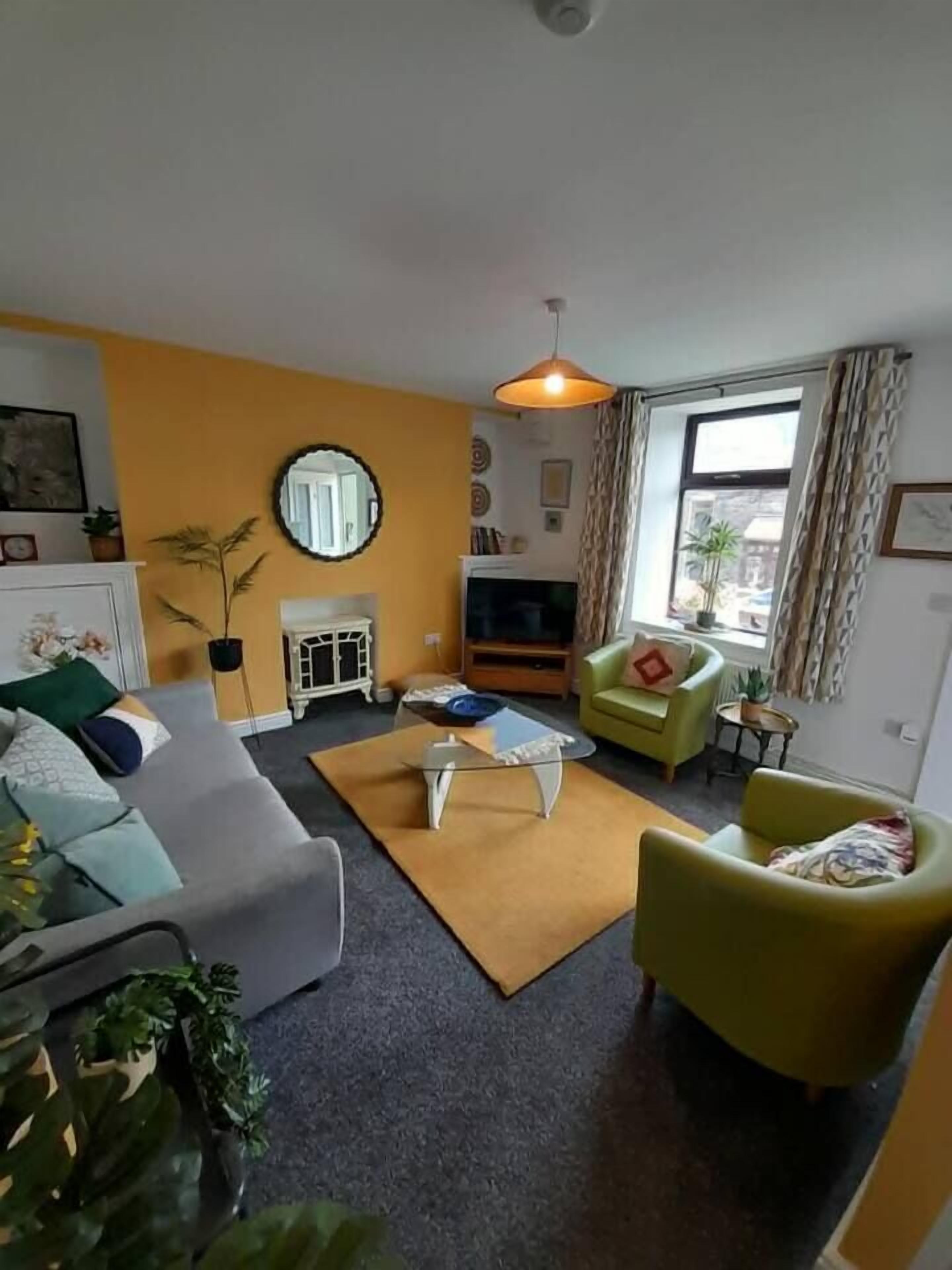 A living room with a sofa, armchairs, a coffee table, a TV, and a fireplace.