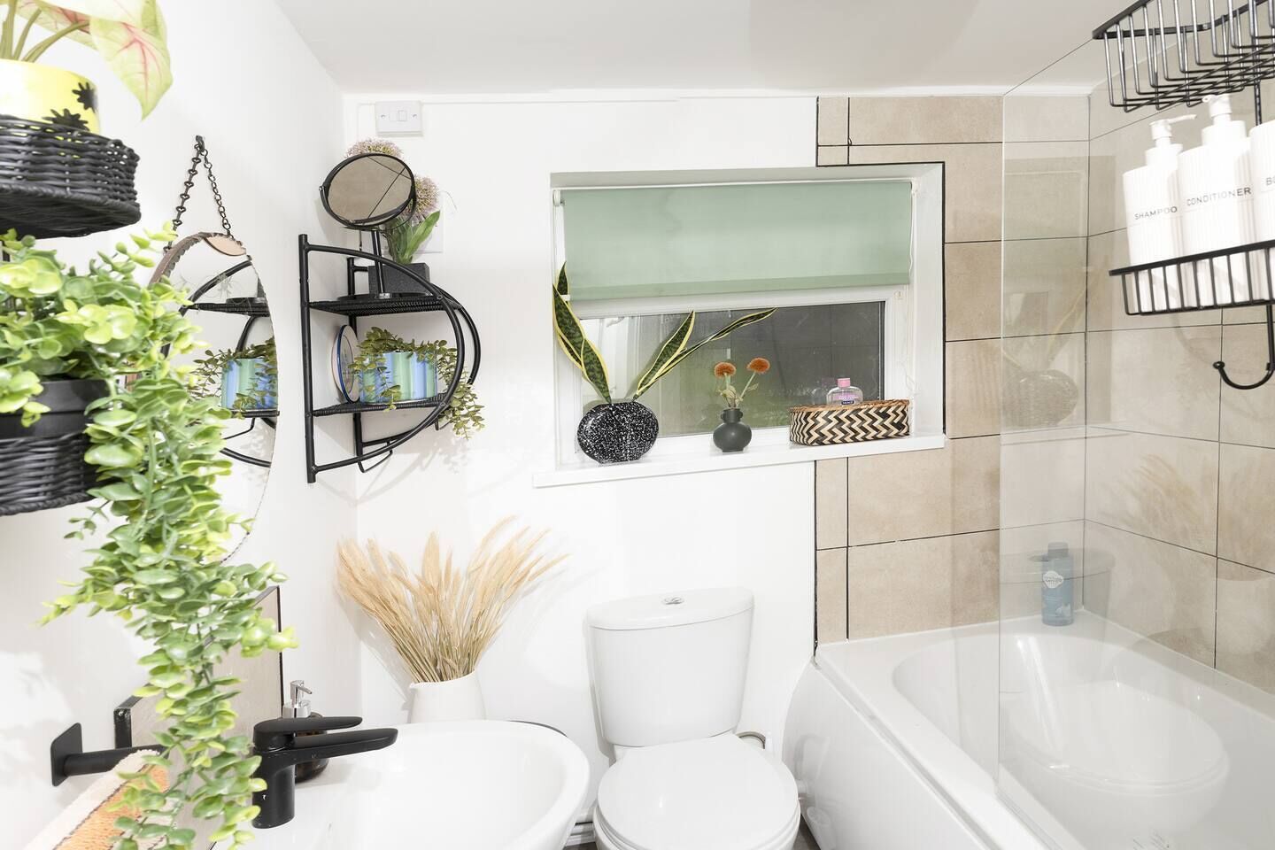 A modern bathroom with a toilet, sink, and bathtub. There are shelves with toiletries and a mirror above the sink.