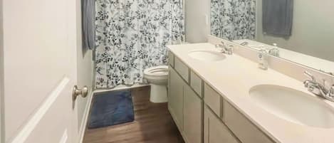 A bathroom with two sinks, a toilet, and a shower curtain with a floral pattern.
