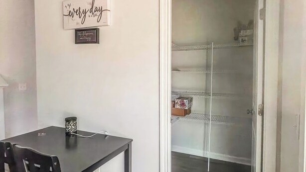 Un comedor con mesa y sillas, una pared con citas motivacionales y vista a otra habitación con puerta de vidrio.