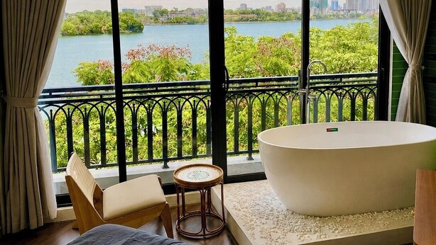 Una camera da letto con un letto grande, una vasca e vista su un lago e sullo skyline della città.