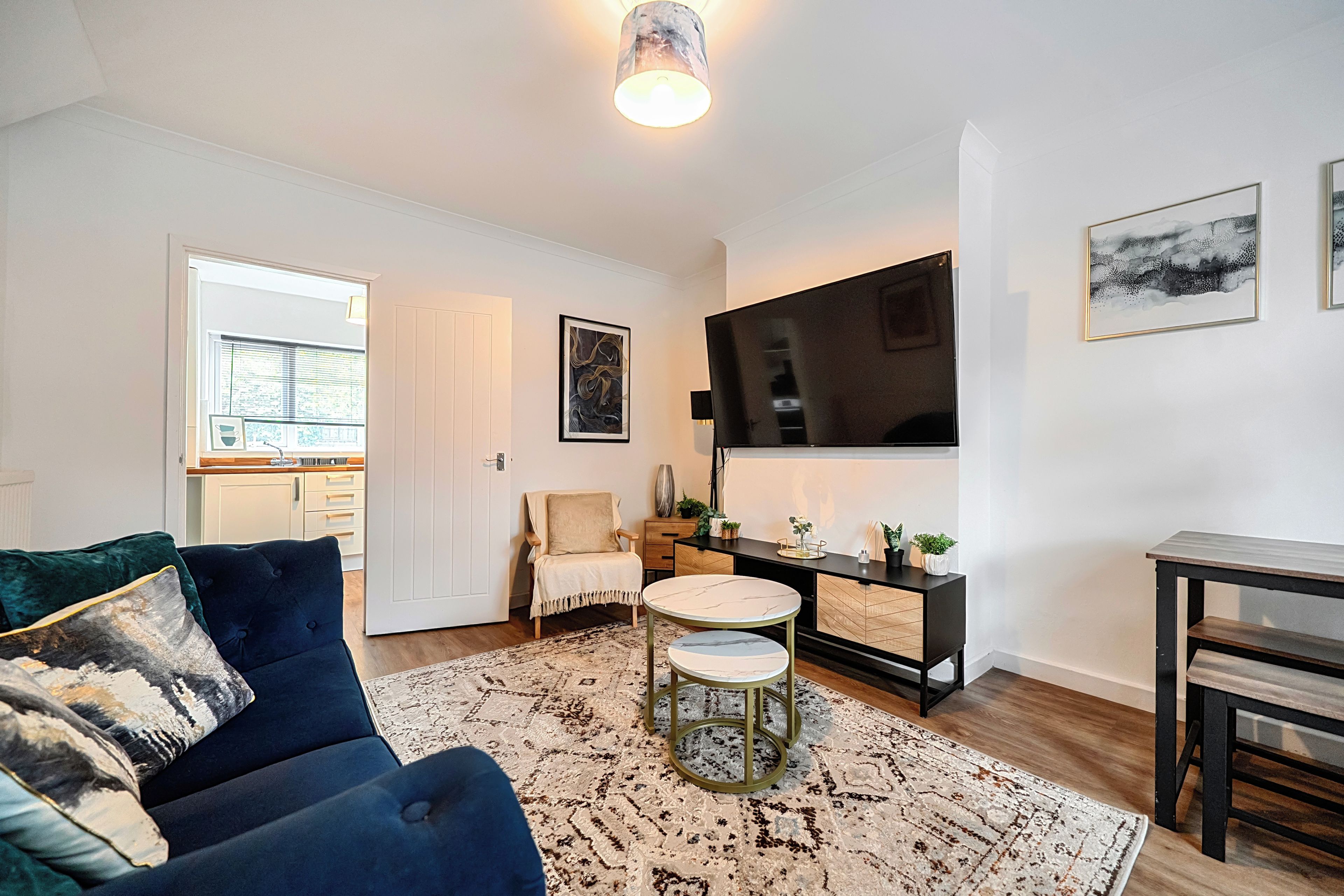 A modern living room with a sofa, a coffee table, a TV, and a dining area with a table and chairs.
