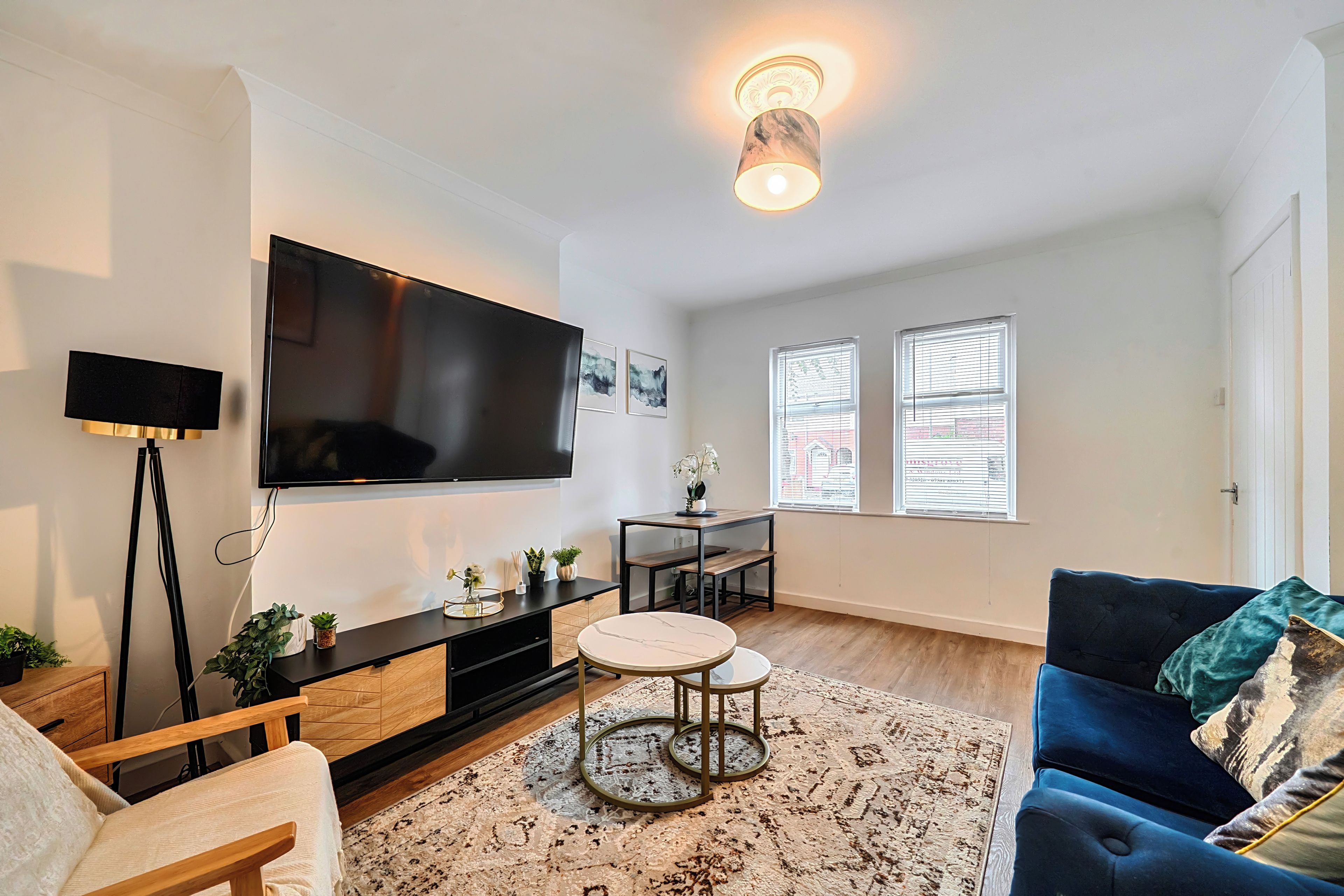 A modern living room with a flat-screen TV, a coffee table, a sofa, and a patterned rug.