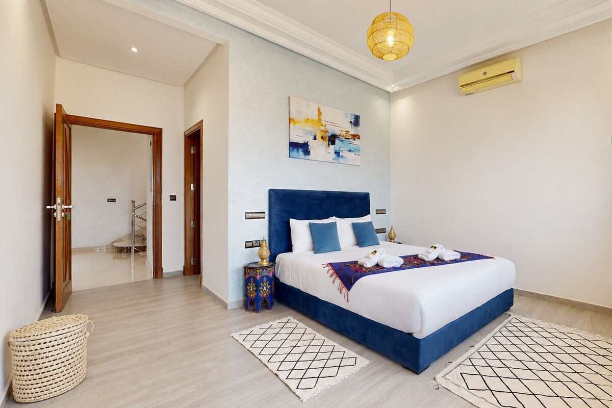 Habitación de hotel moderna con una cama grande, un cuadro en la pared y una lámpara en el techo.